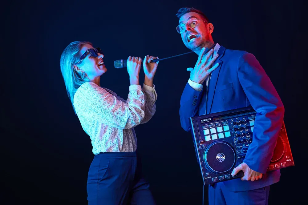 Traurednerin Julia Koch singt ins Mikrofon, Trauredner Robin Rehmann hält einen DJ-Controller